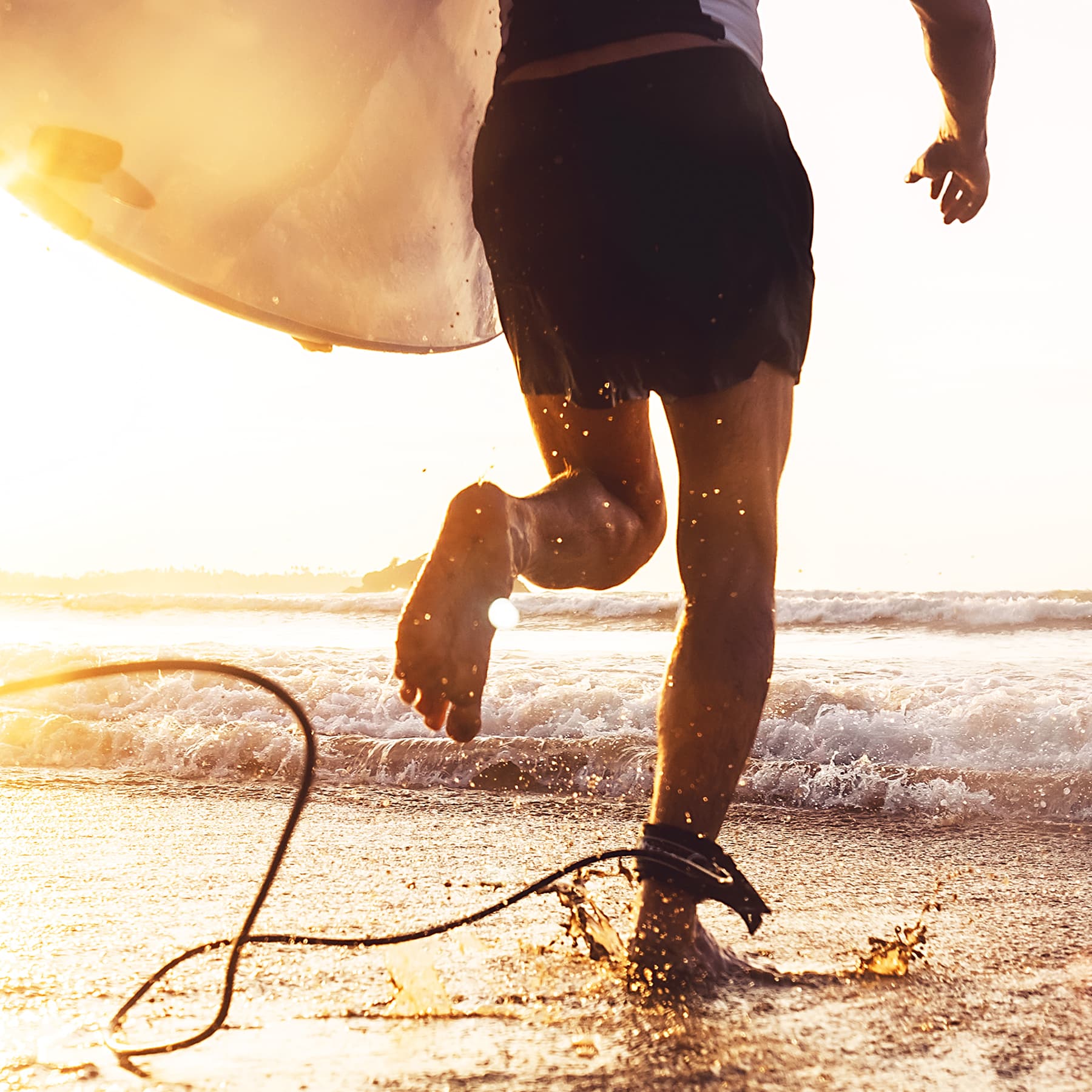 Man with surfboard running into the ocean waves.