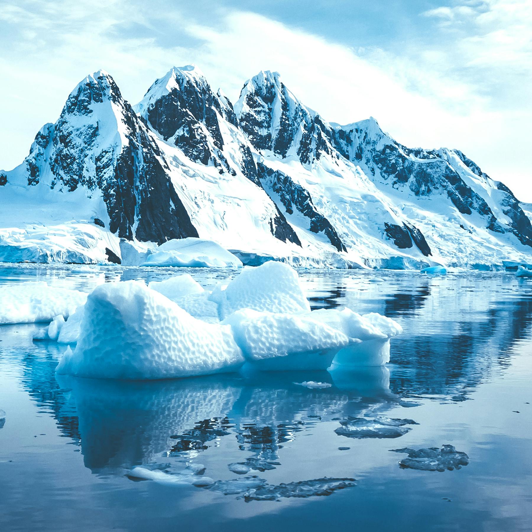 Computer render of a snow covered mountain with ocean waters in front of it along with small icebergs.