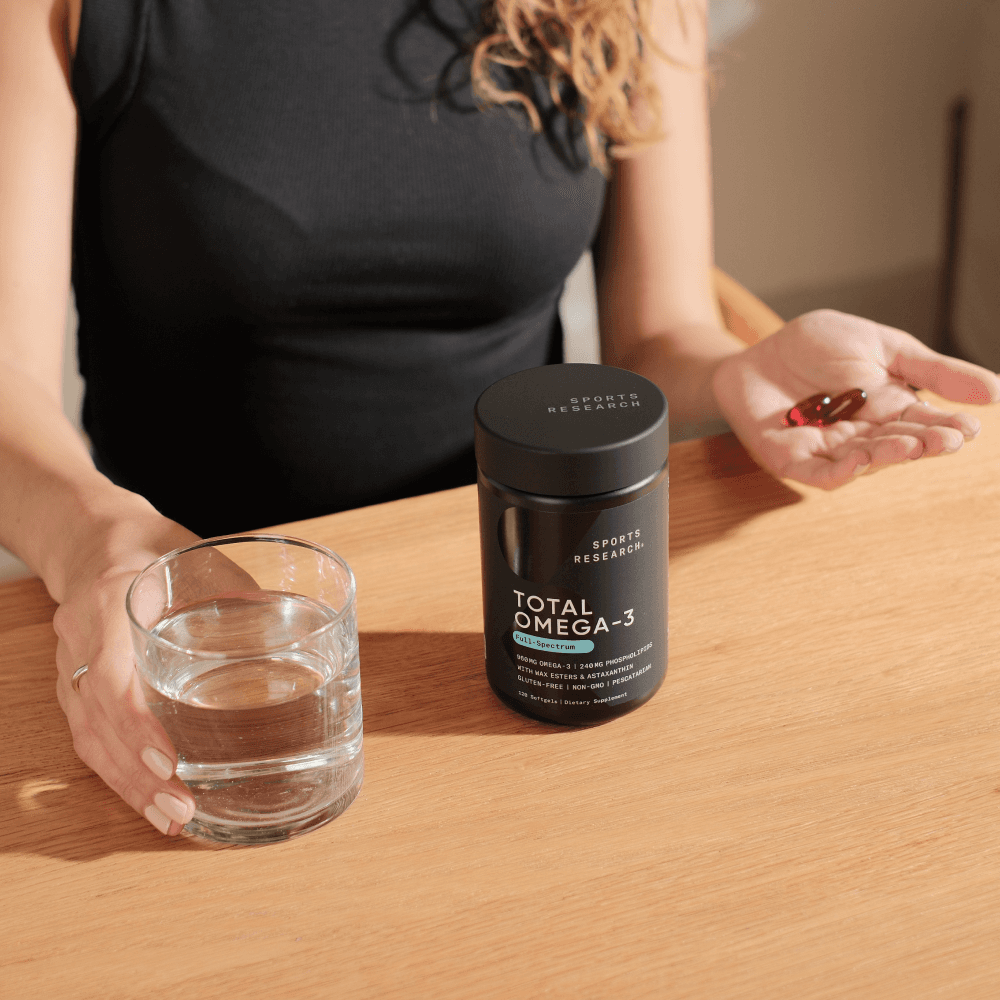 Lifestyle image of woman holding total omega.