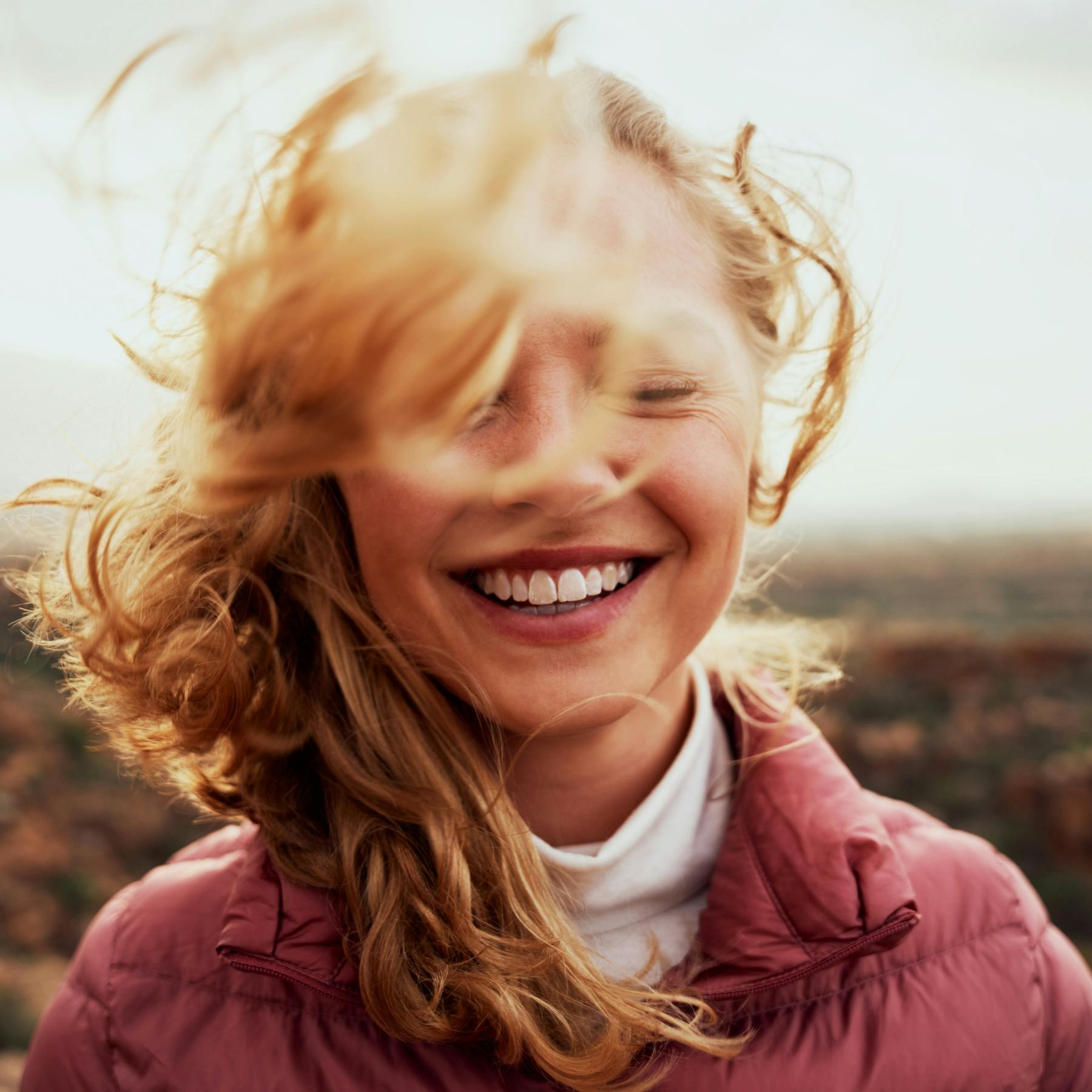 Woman outside smiling with hair blowing around her face.