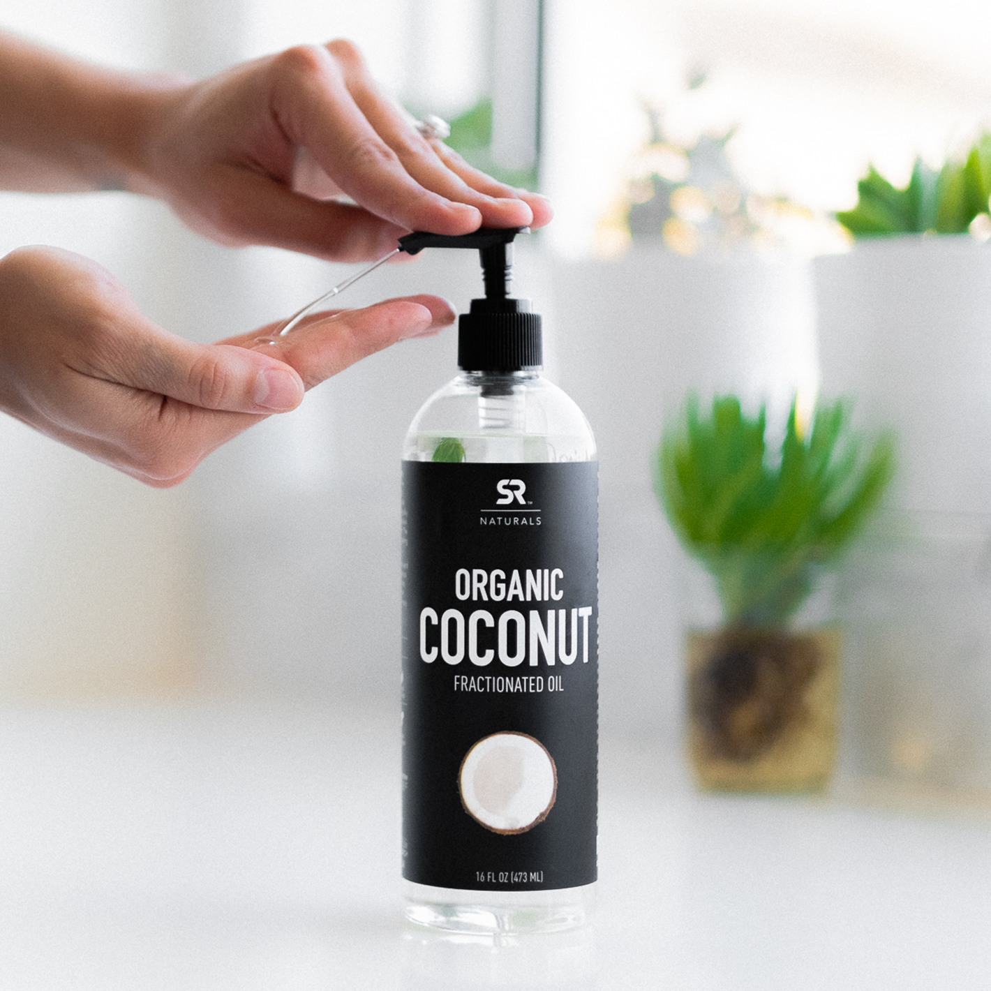 Woman pumping Sports Research Naturals Fractionated Organic Coconut oil out of the bottle into her hands.