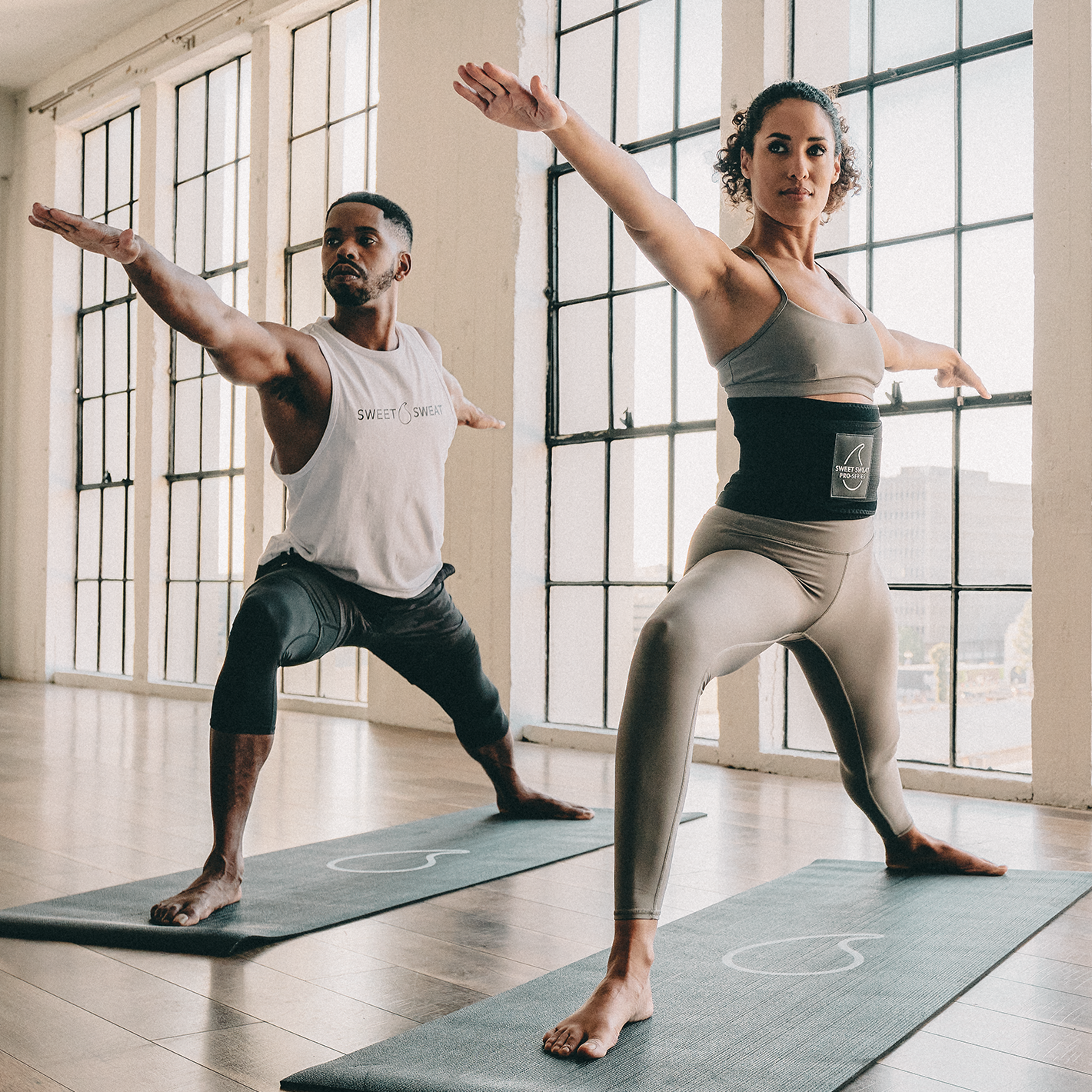 A man and woman practicing yoga poses on a Sweet Sweat yoga mat.