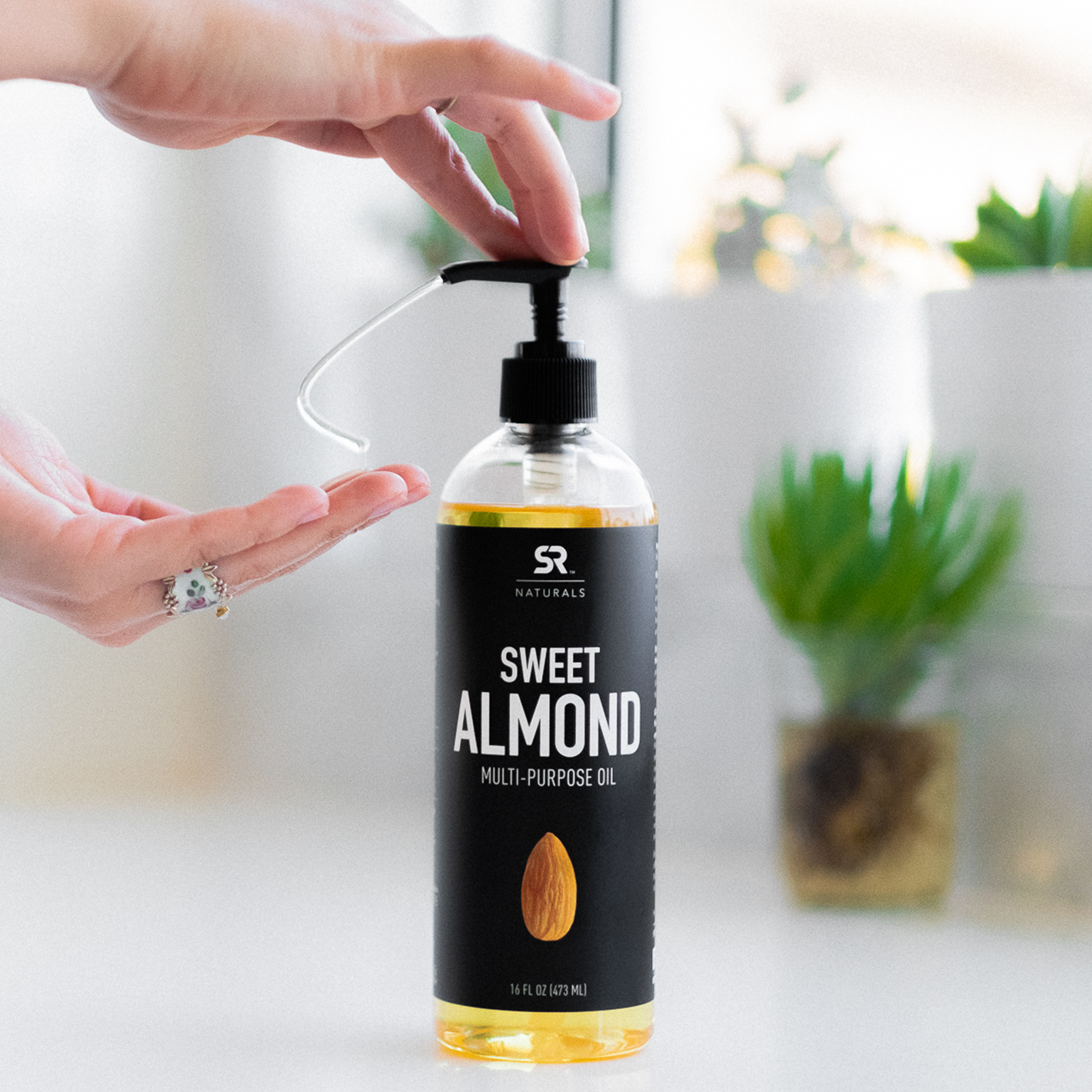 Woman pumping out Sports Research Naturals Sweet Almond Oil into her hand from the bottle.