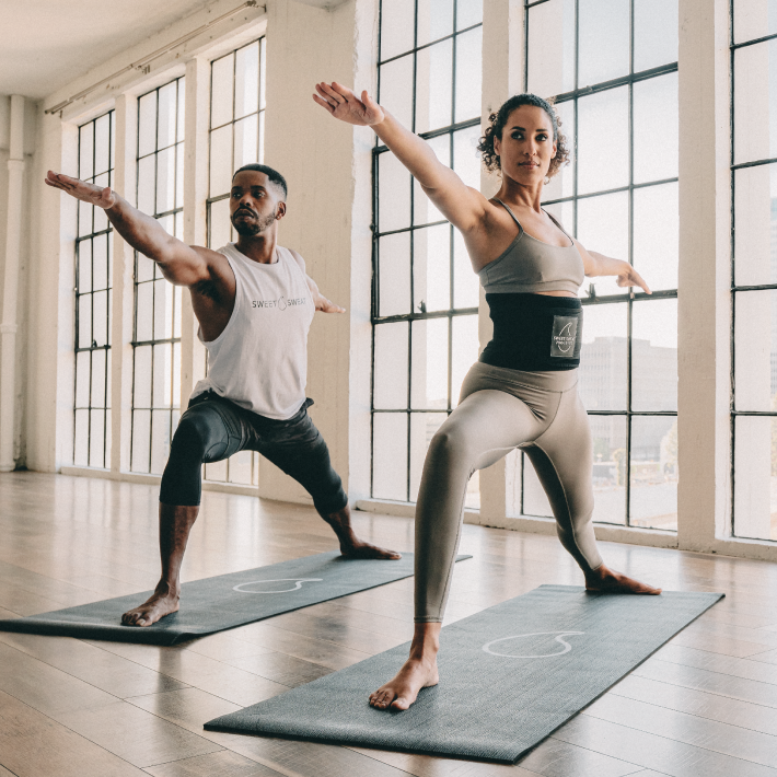 a man and a woman doing yoga in a large room.