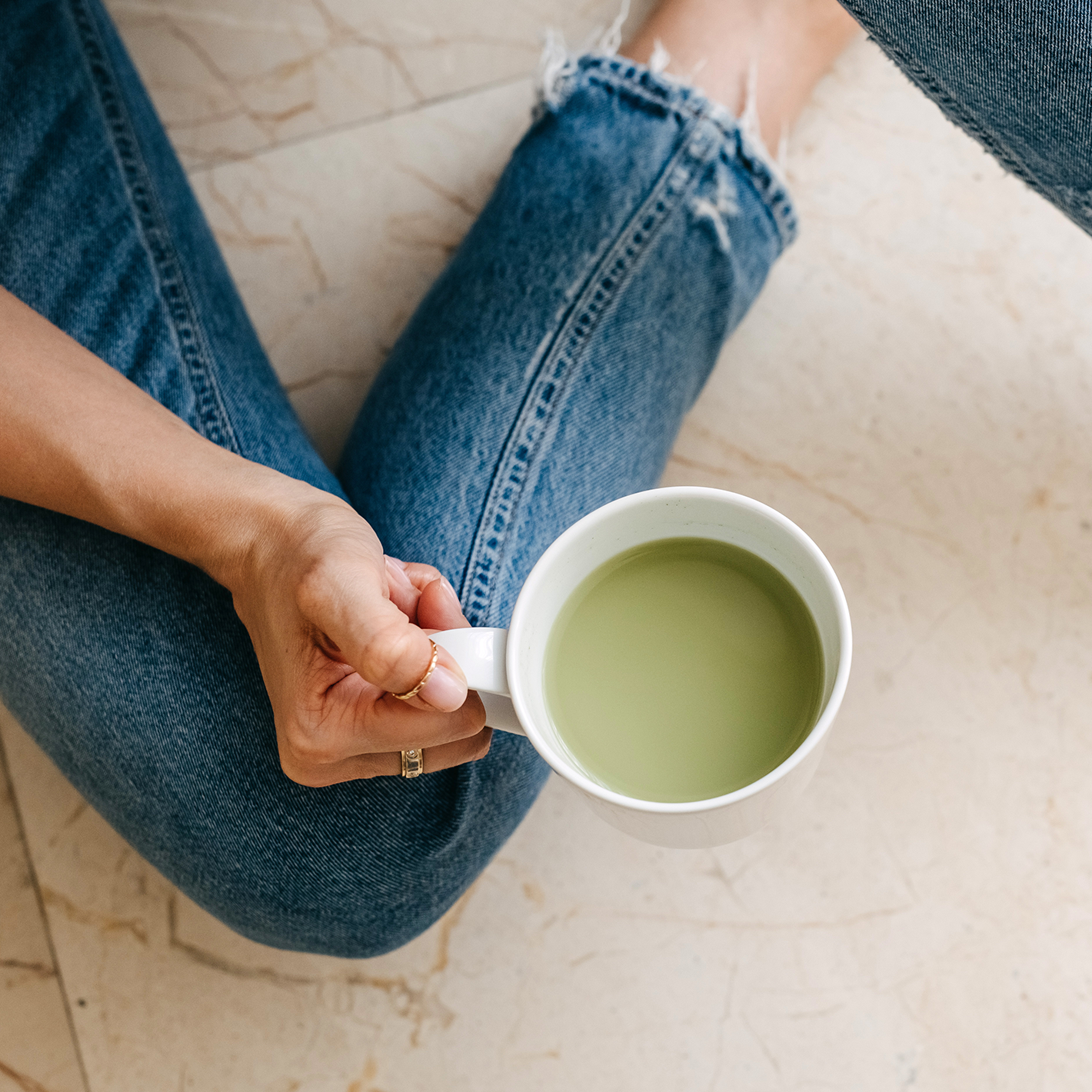 Woman sitting down holding a mug of a Collagen Matcha Green Tea based drink. 